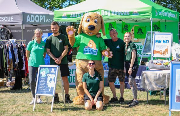Jerry Green Dog Rescue stand at county show with people and dog mascot.
