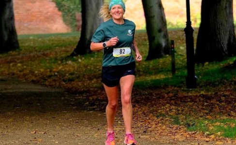 A blonde female running in a green Jerry Green Dog Rescue t-shirt