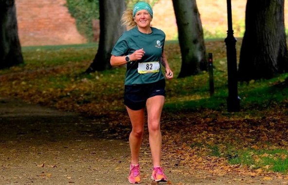 A blonde female running in a green Jerry Green Dog Rescue t-shirt