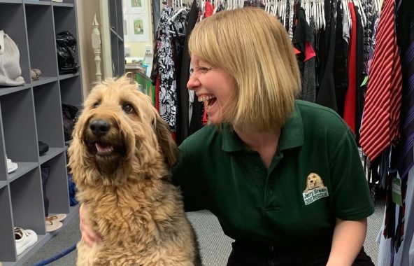 Laughing young, blonde haired, lady with golden, curly coated dog.