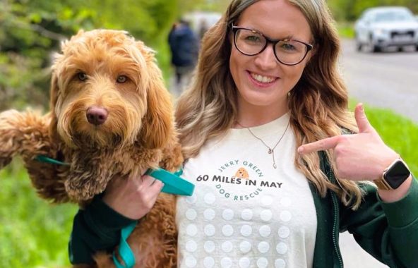 Young woman holding a tan cockapoo.
