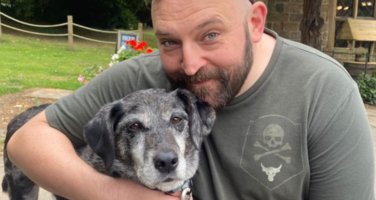 A photo of a fundraiser with their arm around their rescue dog.