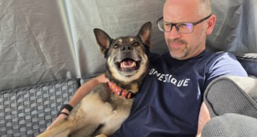 Harper, a German Shepherd Cross, sitting with her foster carer and smiling.