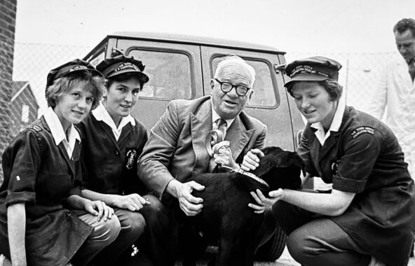 Black and white photo of Jerry Green and 3 ladies in Jerry Green Dog Rescue uniform from 1961 caring for a large black dog