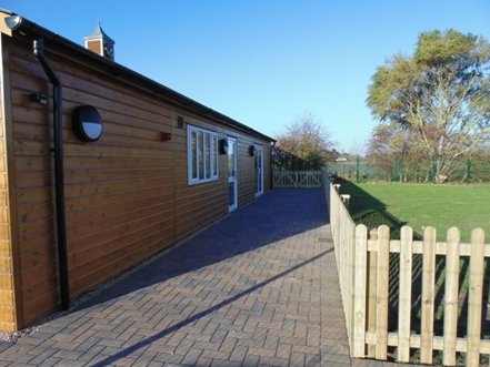 Side of building with fenced paddock.
