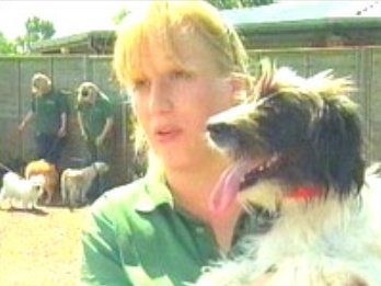 Blonde lady holding black and white shaggy dog