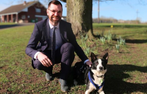Man kneeling in a field with a black and white border collie.