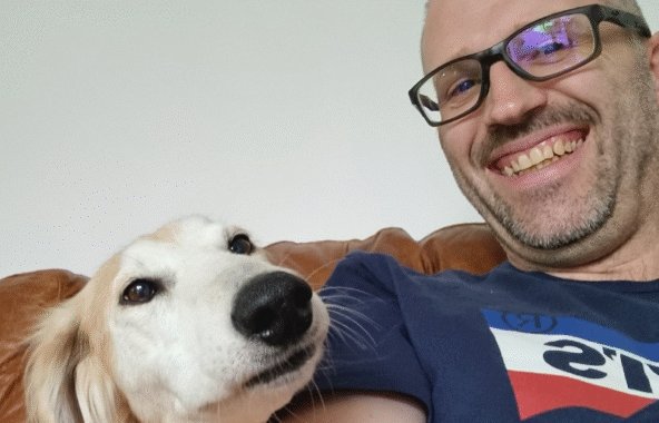 Smiling man with a tan and white dog.
