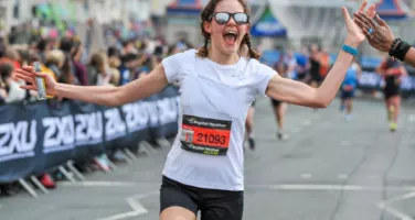 Image of person running the Brighton Marathon, high fiving the crowd