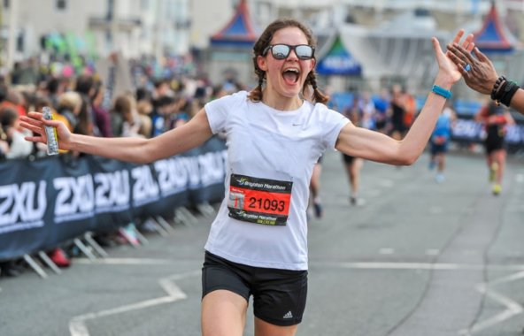 Image of person running the Brighton Marathon, high fiving the crowd