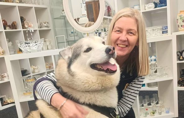 Blonde haired woman with very fluffy husky, in a shop.