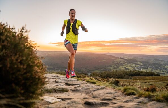 Runner in yellow t-shirt and shorts on stony path high on a hillside.